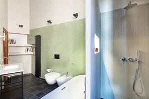 Une salle de bain moderne équipée d’une baignoire, d’une douche, de toilettes et d’un bidet.