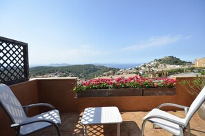 A balcony with two chairs and a table, overlooking a town with a hill and flowers in the foreground. - Holiday rental semidetached with swimming pool in Begur, Centre (Begur)