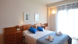 A hotel room with a bed, a wooden dresser, two bedside tables with lamps, and a window with curtains. - Holiday rental semidetached with swimming pool in Begur, Centre (Begur)