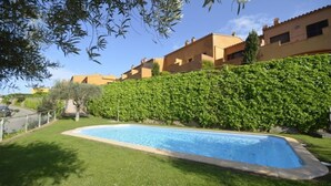 A swimming pool surrounded by well-maintained grass and a hedge, with buildings in the background. - Holiday rental semidetached with swimming pool in Begur, Centre (Begur)