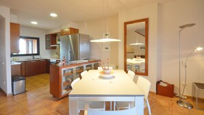 A modern kitchen with a dining area, featuring a stainless steel refrigerator, white cabinets, and a tiled floor. - Holiday rental semidetached with swimming pool in Begur, Centre (Begur)