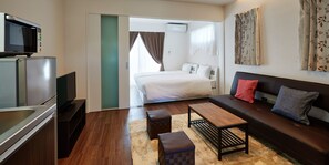 Una habitación de hotel moderna con kitchenette, un sofá, una mesa de centro y una cama.