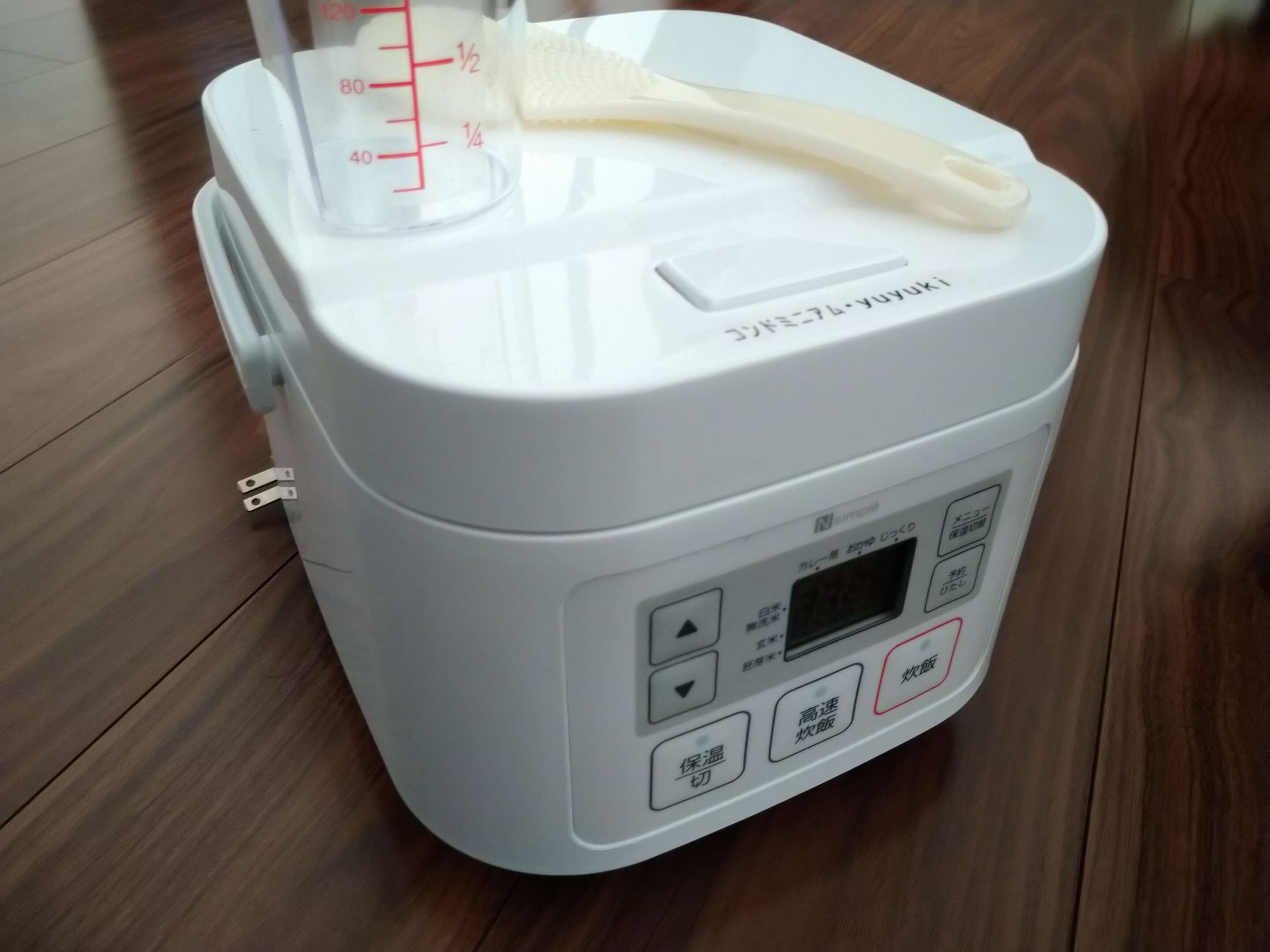 Een witte rijstkoker met een digitaal display en knoppen voor instellingen.