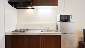 A modern kitchen with a gas stove, a built-in microwave, and a refrigerator. - Condominium･yuyuki (Yomitan)