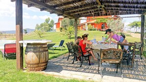 An outdoor patio with a rustic wooden pergola, a stone barrel, and a table set for a meal.