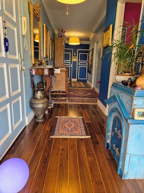 A hallway with wooden flooring, a blue door, a mirror, and a lamp. - SPLENDID F3 SWIMMING POOL LIVING ROOM PANORAMIC BREATHTAKING 180° SEA🌊 MARINA⛵ PLAGE⛱️ (Saint-Gilles les Bains)