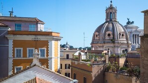Un edificio storico con una cupola e un campanile, circondato da palazzi residenziali con balconi e tetti in terracotta.