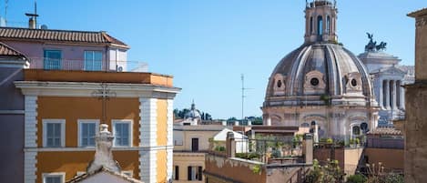 Un edifici històric amb una cúpula i un campanar, envoltat d'edificis residencials amb balcons i teulades de terracota.