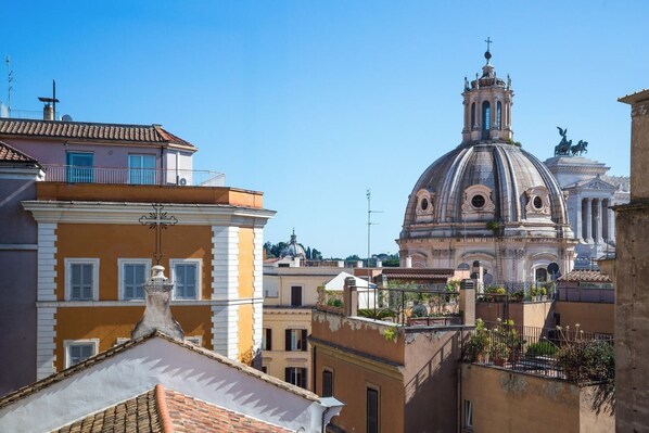 A historic building with a dome and bell tower, surrounded by residential buildings with balconies and terracotta roofs.
