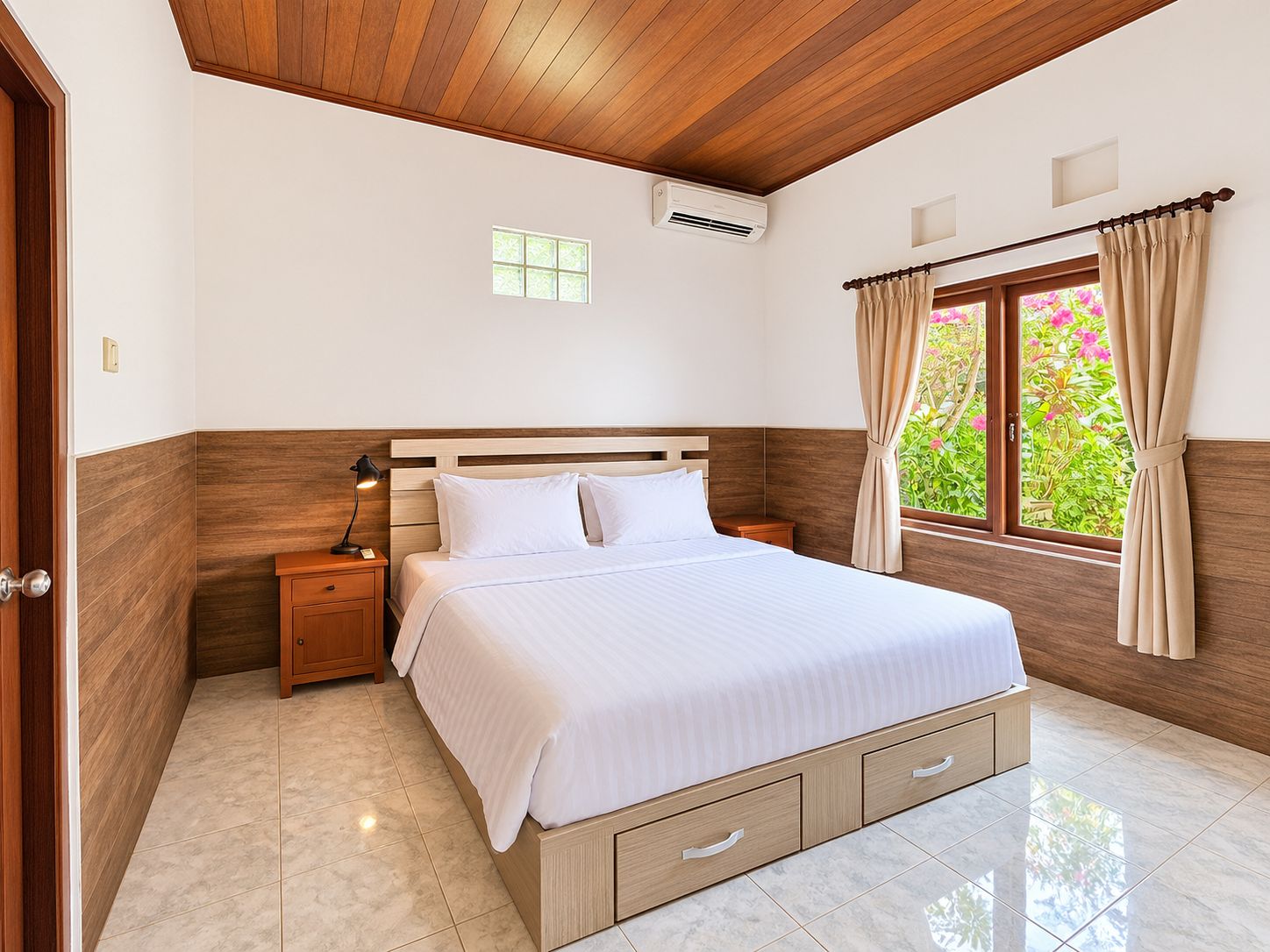 A bedroom with a wooden ceiling, a bed with white bedding, a nightstand, a bedside lamp, and a window with curtains.