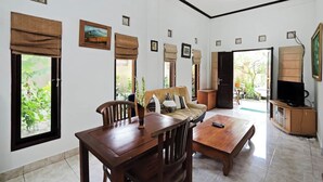 A spacious living room with a wooden dining table, a sofa, and a TV. - Rumah Akira Seminyak (Seminyak)