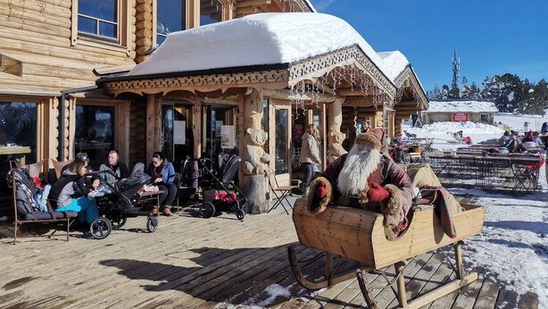 A wooden building with a snow-covered roof and a sled with a Santa figure.