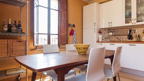 A kitchen with a wooden table, white chairs, and a window with wooden shutters. - Medieval village TOP flat, third floor with Wi-Fi & aircon (Compignano)