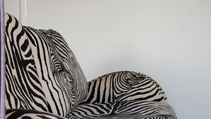Un canapé à rayures zébrées dans une pièce dont le mur est d’un blanc uni et où est accroché un tableau encadré.