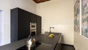 Una cucina moderna con mobili neri, un bollitore in acciaio inossidabile e un forno integrato.
