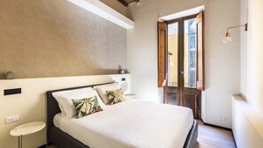 Una camera da letto con un letto, un tavolino rotondo, una finestra vista e un soffitto con travi a vista.