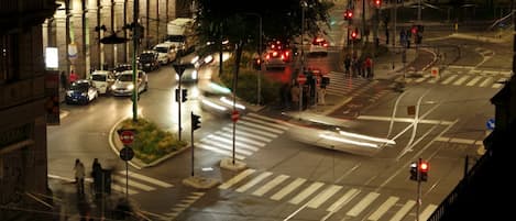 Cruzamento urbano noturno com semáforos, veículos e pedestres.