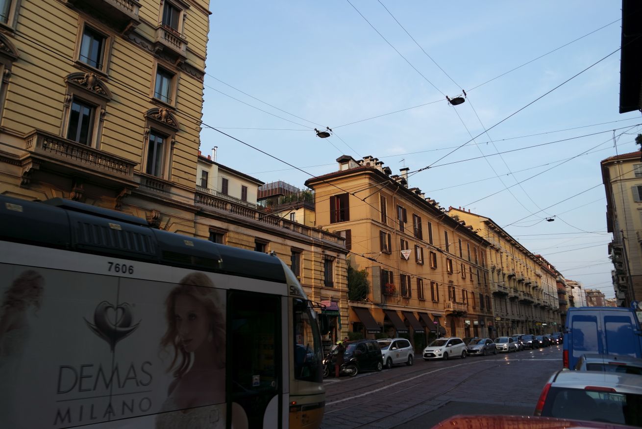 A street scene with a tram, parked cars, and multi-story buildings.