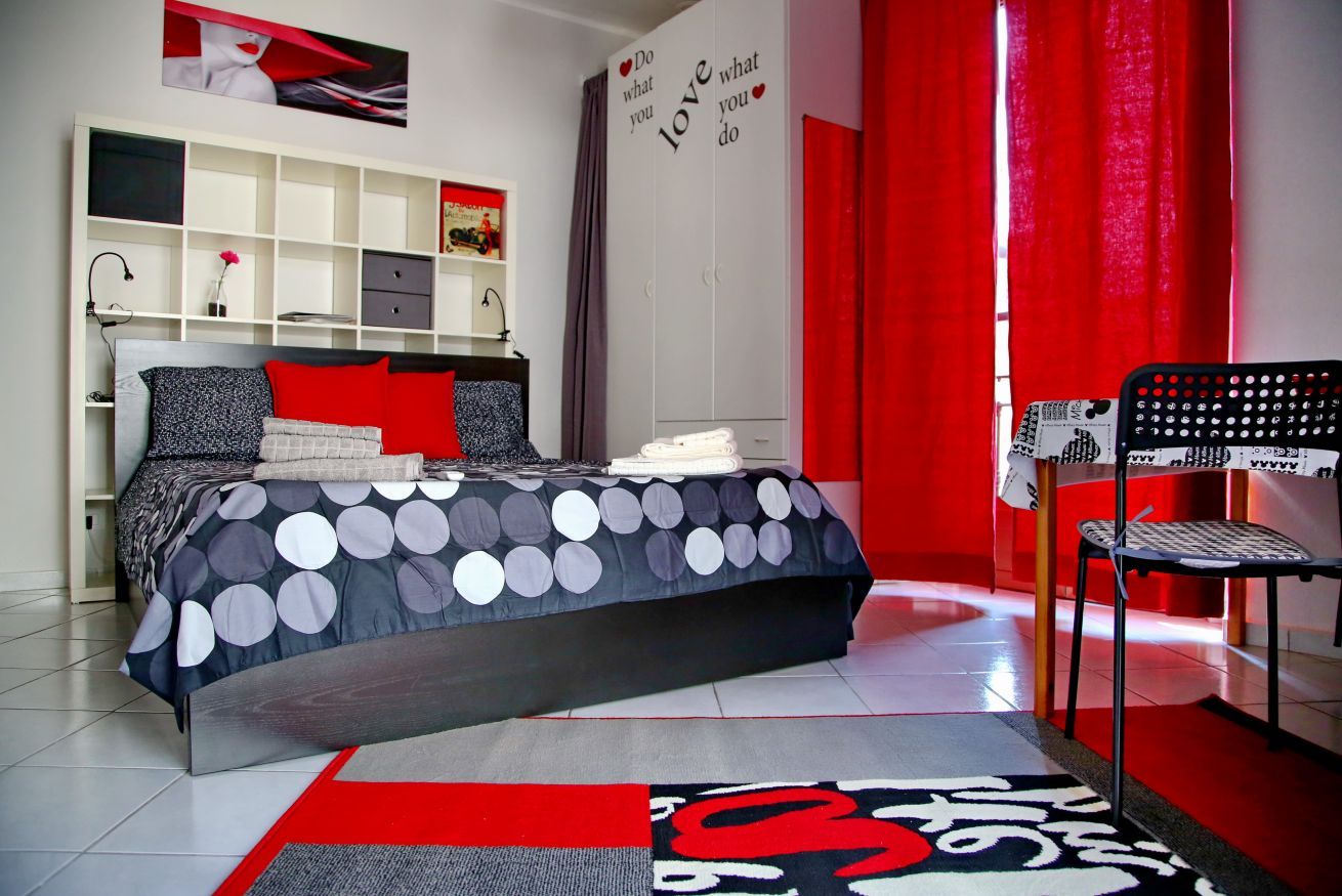 Un dormitorio con cama, una silla, un armario y una estantería.