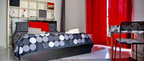 Een slaapkamer met een bed, een stoel, een kledingkast en een plank.