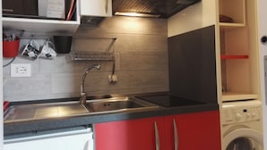 A compact kitchen with a microwave, stove, sink, and a washing machine. - Nice and bright apartment with wi-fi and a/c in Darsena and Navigli district (Milano)