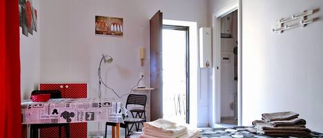 Un dormitorio con una cama, un escritorio, una silla, una mesa y una puerta que da a otra habitación.