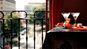 Un balcon avec une table dressée pour deux personnes, comprenant deux verres à martini et une assiette de nourriture.