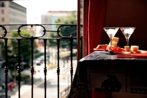 Un balcon avec une table dressée pour deux personnes, comprenant deux verres à martini et une assiette de nourriture.