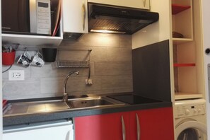 Une cuisine compacte équipée d’un four à micro-ondes, d’une cuisinière, d’un évier et d’un lave-linge.