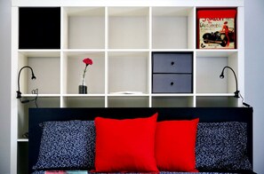 A bedroom with a bed, a nightstand, a shelf with a vase of flowers, and a book. - Nice and bright apartment with wi-fi and a/c in Darsena and Navigli district (Milano)