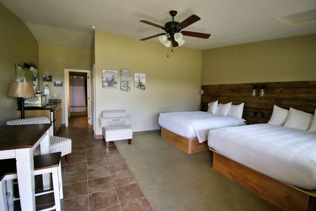 A hotel room with a bed, two bedside tables, a desk, a chair, and a ceiling fan.
