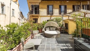 A courtyard with a round wicker sofa, a table, and chairs. - FONTANELLA BORGHESE PALACE (Roma)