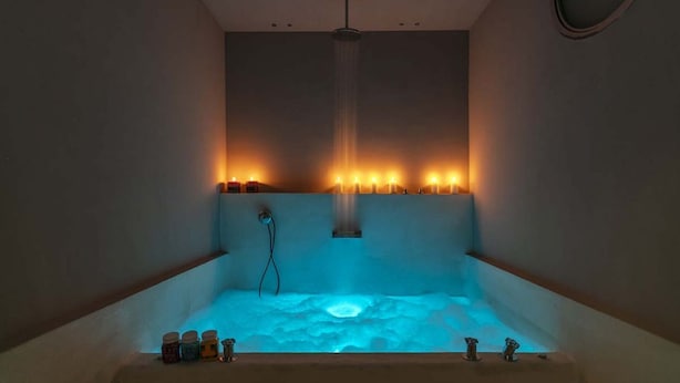 A spa room with a bathtub, candles, and a ceiling shower. - FONTANELLA BORGHESE PALACE (Roma)
