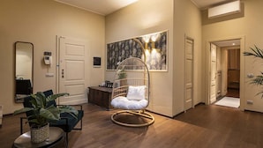 A modern interior with a wooden floor, a hanging chair, a small table with a plant, and a wall-mounted artwork. - FONTANELLA BORGHESE PALACE (Roma)