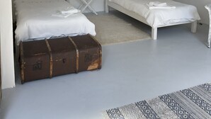 Una habitación con dos camas, un banco de madera y una maleta.