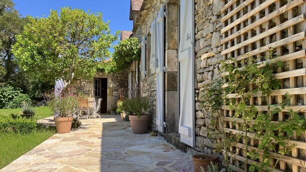 A stone pathway leading to a rustic stone building with a wooden lattice wall.