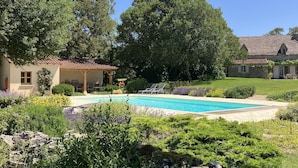 A pool surrounded by lush greenery and stone buildings.