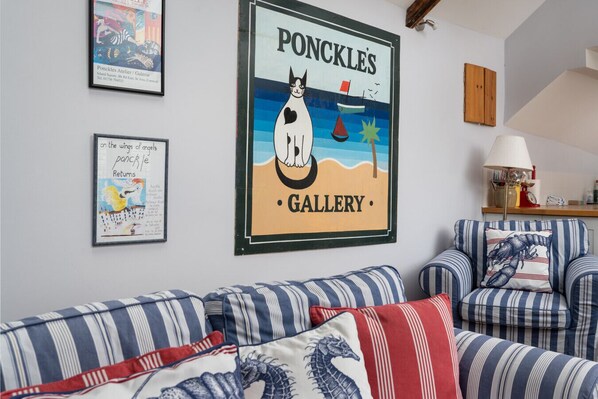 A room with striped sofas, a framed poster of a cat on a beach, and a wooden cabinet. - Famous Artist's Residence Near to St Ives Harbour (Saint Ives)