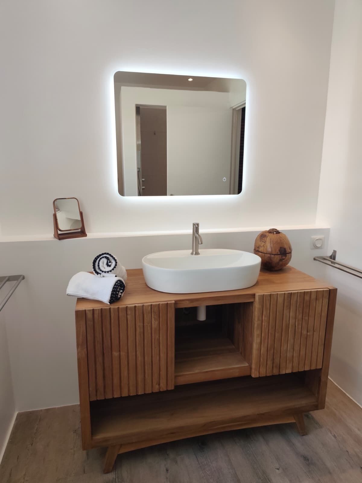 A bathroom with a wooden vanity, a white sink, a mirror, and a towel.
