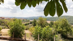 A rural landscape with a stone wall, trees, and a distant view of houses and hills. - Medieval village flat, second floor with Wi-Fi & aircon (Compignano)