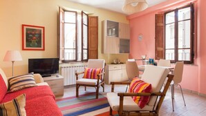 A cozy living room with a sofa, armchairs, a TV, and a dining area with chairs and a table. - Medieval village flat, second floor with Wi-Fi & aircon (Compignano)