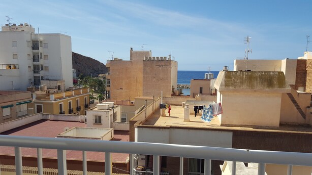 Zona residencial com vários edifícios, uma varanda com roupa a secar e vista para o mar.