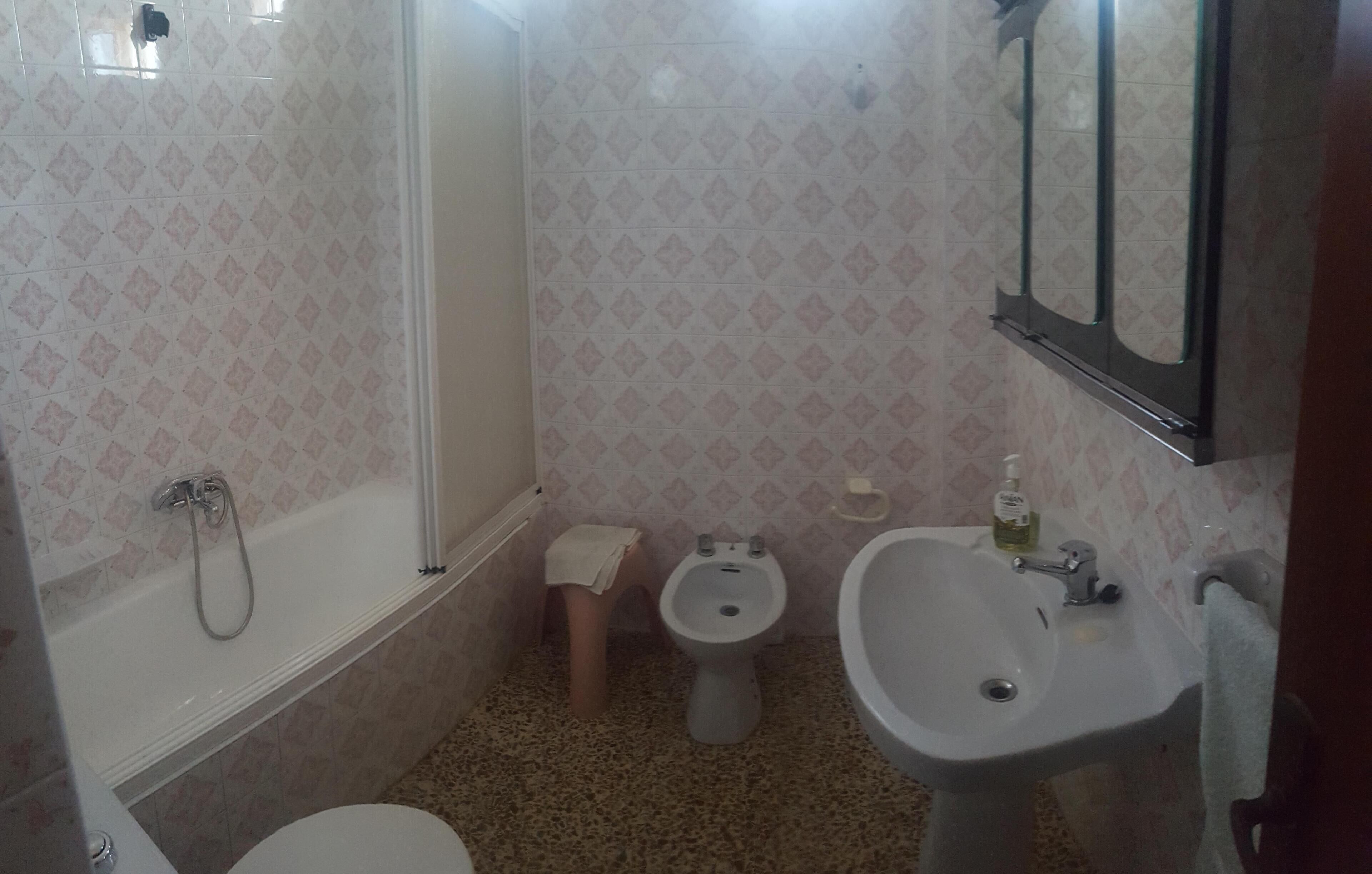 A small bathroom with a toilet, bidet, bathtub, and sink.