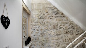 A stone wall, a heart-shaped sign, a white staircase, and a black object on a shelf. - Piazza Salvatore, 7, rooms with a view (Ragusa)