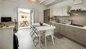 A modern kitchen with white cabinetry, a dining area with a white table and chairs, a TV, and a red pendant light. - Piazza Salvatore, 7, rooms with a view (Ragusa)