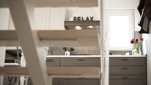 A kitchen with a 'RELAX' sign, wooden cabinets, and a vase with flowers on the counter. - Piazza Salvatore, 7, rooms with a view (Ragusa)