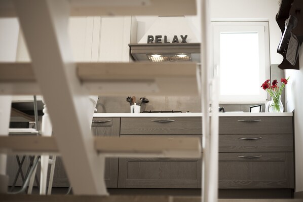 A kitchen with a 'RELAX' sign, wooden cabinets, and a vase with flowers on the counter.
