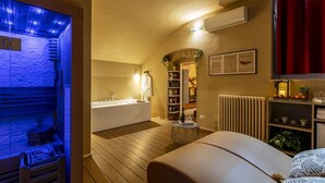 Ein modernes Badezimmer mit einer Badewanne, einem kleinen runden Tisch mit einer Flasche und Gläsern sowie einem Ablagefach mit Toilettenartikeln.