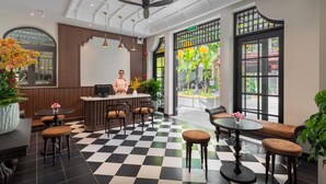 A hotel lobby with a checkered floor, a reception desk, seating areas, and large windows with views. - BACKHOME BOUTIQUE OLD TOWN HOI AN (Da Nang)