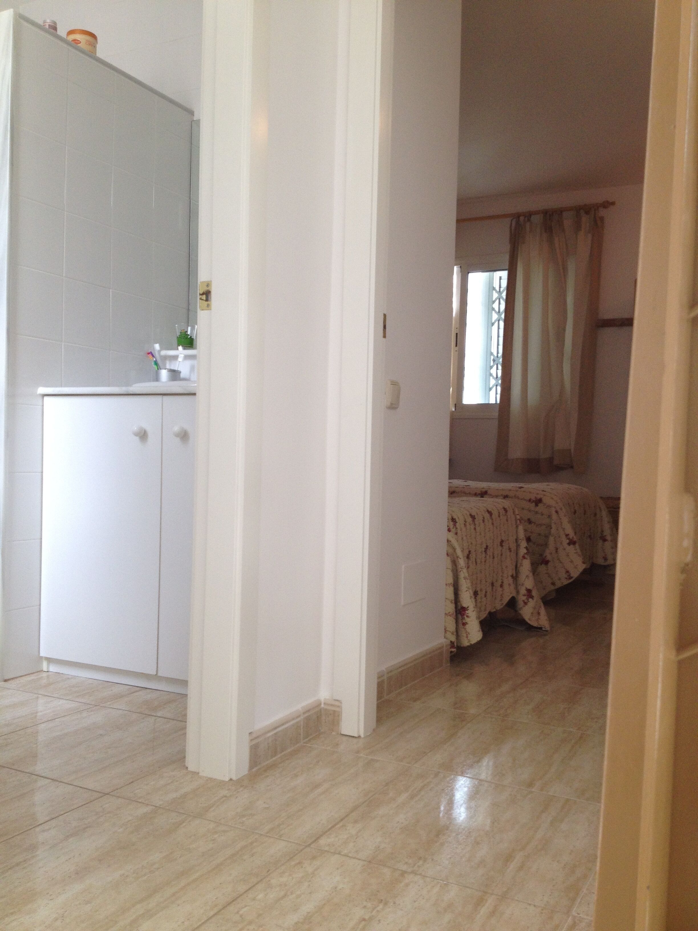 A room with a bed, a bedside table, and a mirror.